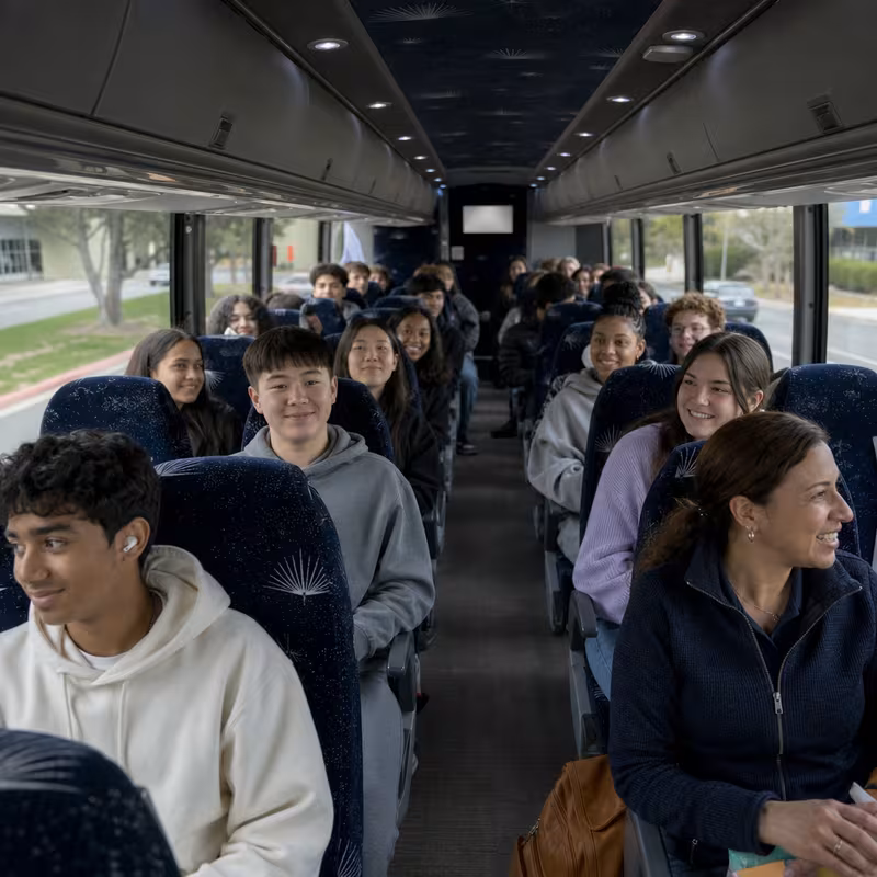Group boarding a white charter bus for School Transportation transportation in Detroit
